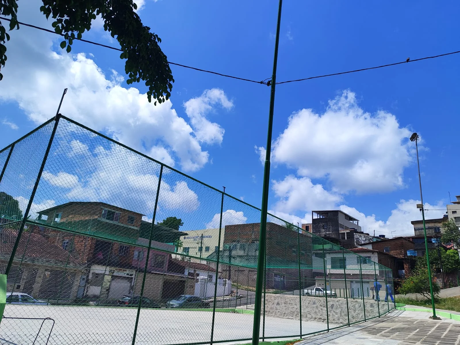 Fechamento do espaço esportivo com estrutura metálica e tela.