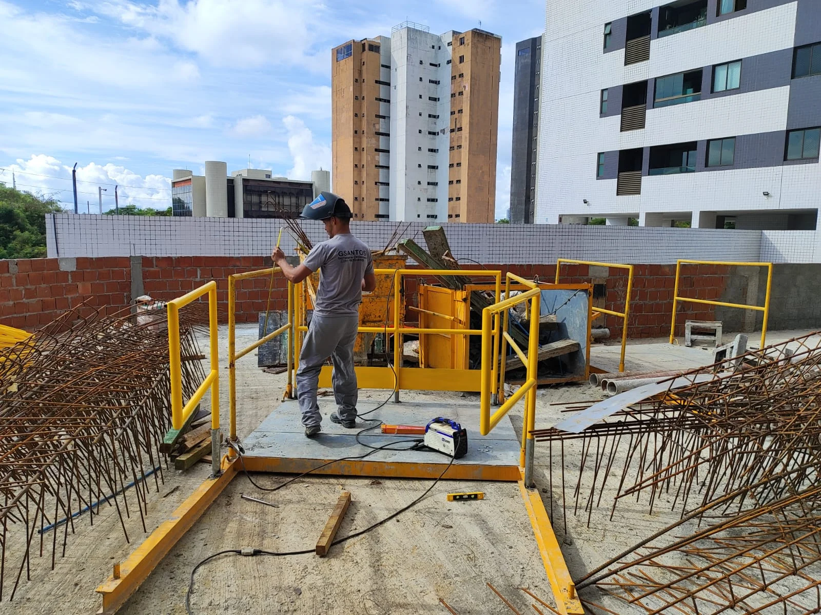 Profissional da G Santos trabalhando em estrutura metálica amarela na obra